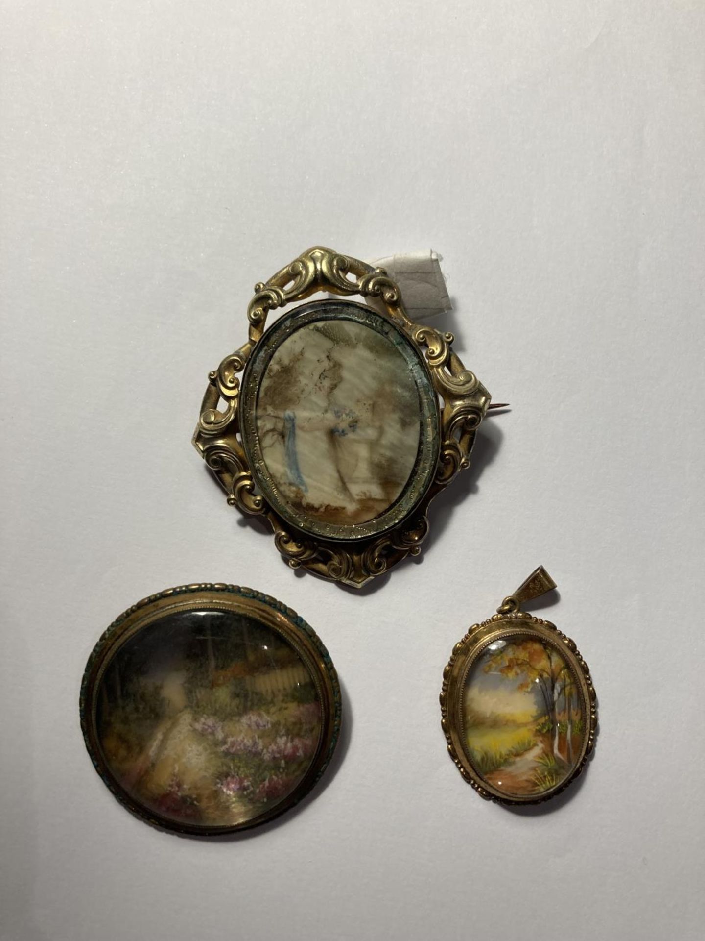 THREE VINTAGE ITEMS OF PICTURES UNDER GLASS TO INCLUDE TWO BROOCHES AND A PENDANT