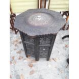 A CARVED INDIAN HARDWOOD TABLE, 22" DIAMETER, WITH FOLDING BASE, FOLIATE CARVING AND INLAY FEATURING