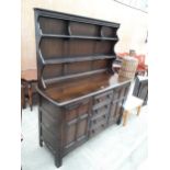 AN ERCOL COLONIAL DRESSER ENCLOSING FOUR DRAWERS AND TWO CUPBOARDS TO THE BASE, COMPLETE WITH