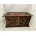 A HEAVILY CARVED JEWELLERY BOX WITH TWO DOORS REVEALING FOUR LINED DRAWERS AND A LIFT UP LID WITH