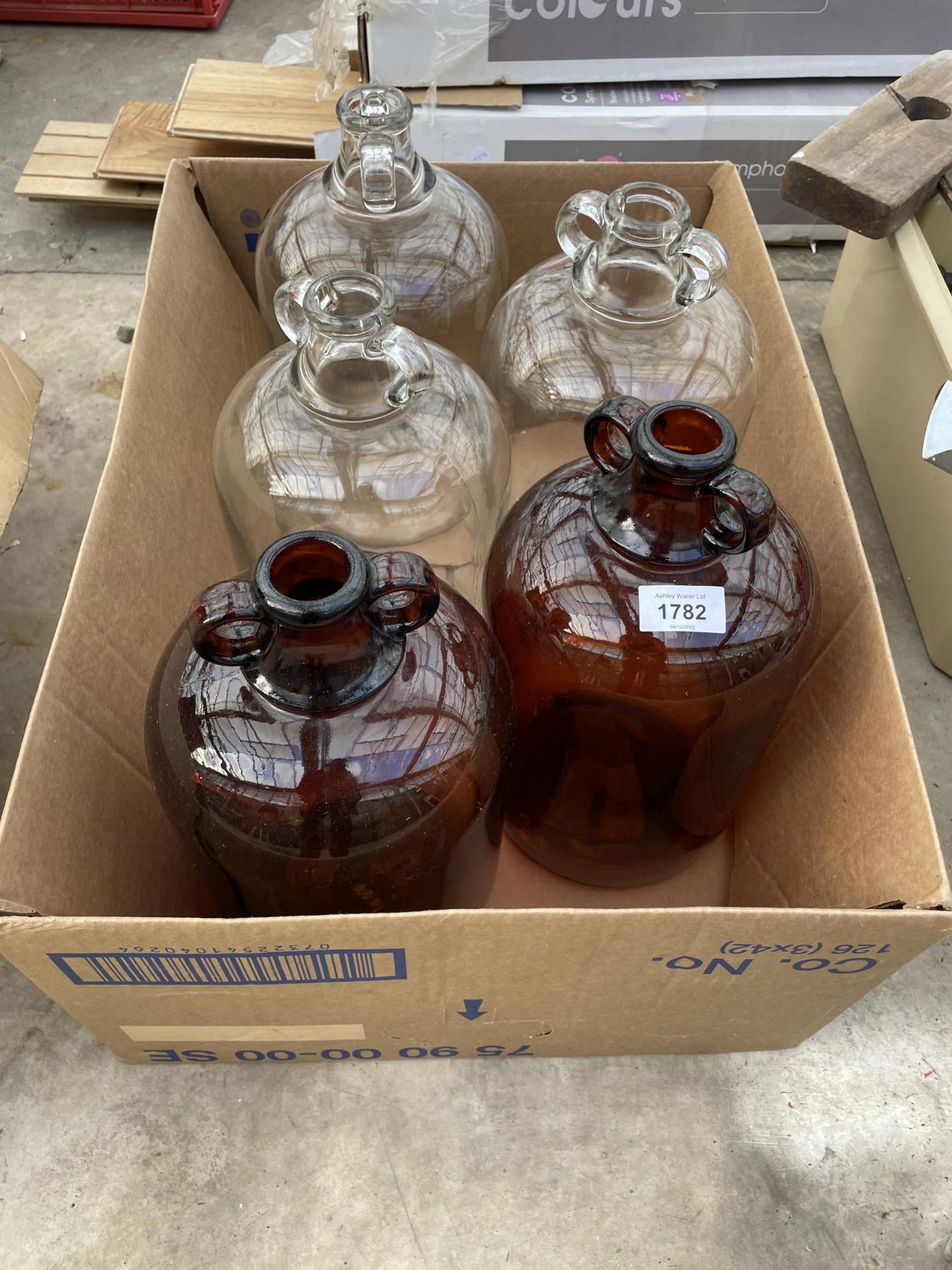 THREE CLEAR GLASS DEMI JOHNS AND A BROWN GLASS DEMI JOHN