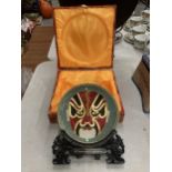 A BOXED ORIENTAL CELADON MASK DESIGN PLATE AND STAND