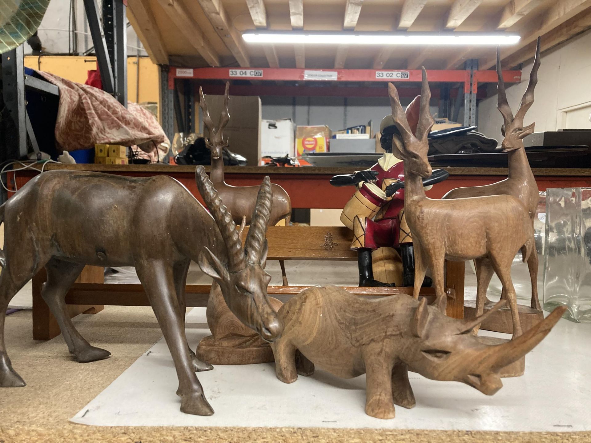 A COLLECTION OF CARVED WOODEN ANIMALS TO INCLUDE ANTELOPES, A RHINOCEROUS, ETC, A BOOK SHELF WITH