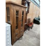 AN OAK CABINET WITH TWO GLAZED DOORS AND SIDES WITH TWO SHORT AND ONE LONG DRAWER