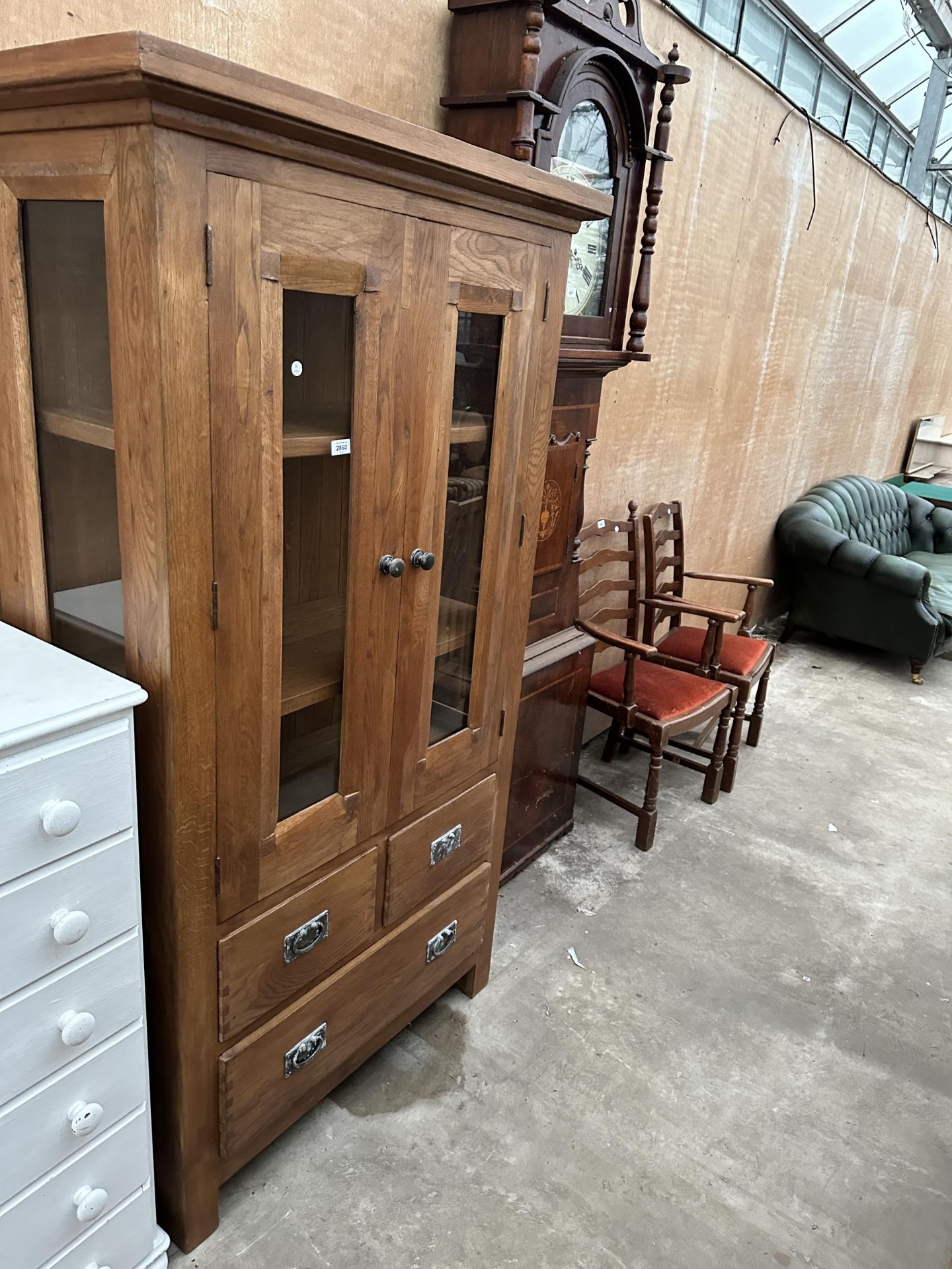 AN OAK CABINET WITH TWO GLAZED DOORS AND SIDES WITH TWO SHORT AND ONE LONG DRAWER