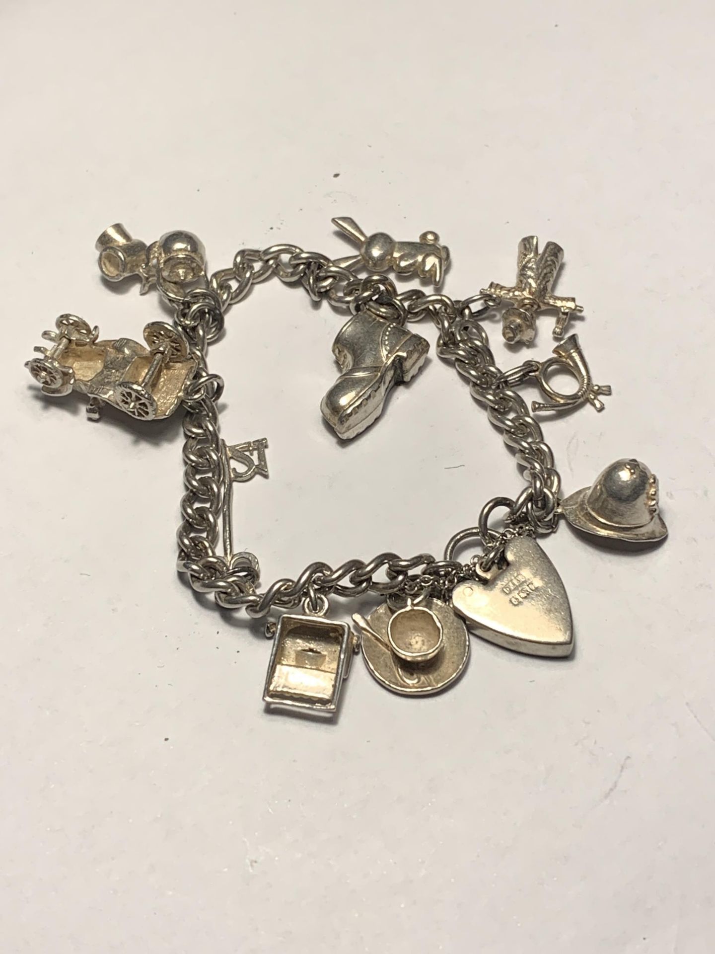 A SILVER CHARM BRACELET WITH ELEVEN CHARMS AND A HALLMARKED BIRMINGHAM SILVER HEART PADLOCK