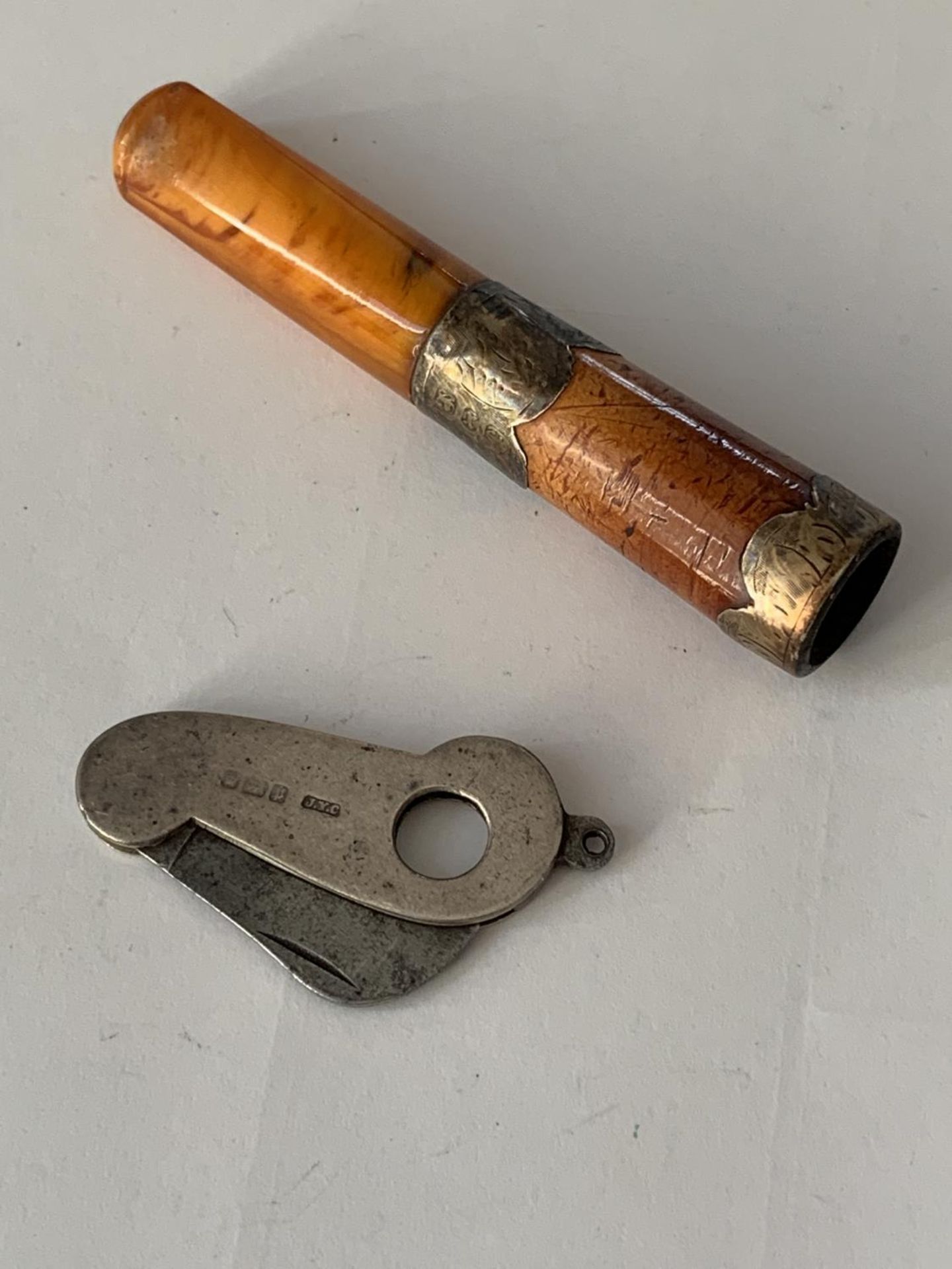 AN AMBER AND HALLMARKED BIRMINGHAM SILVER CHEROOT HOLDER AND A HALLMARKED LONDON SILVER CIGAR CUTTER