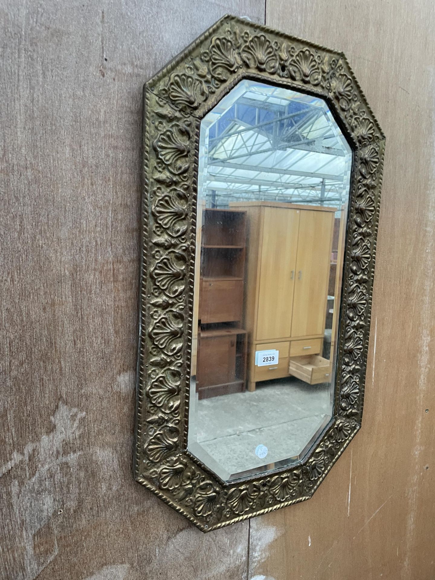 AN EMBOSSED BRASS WALL MIRROR