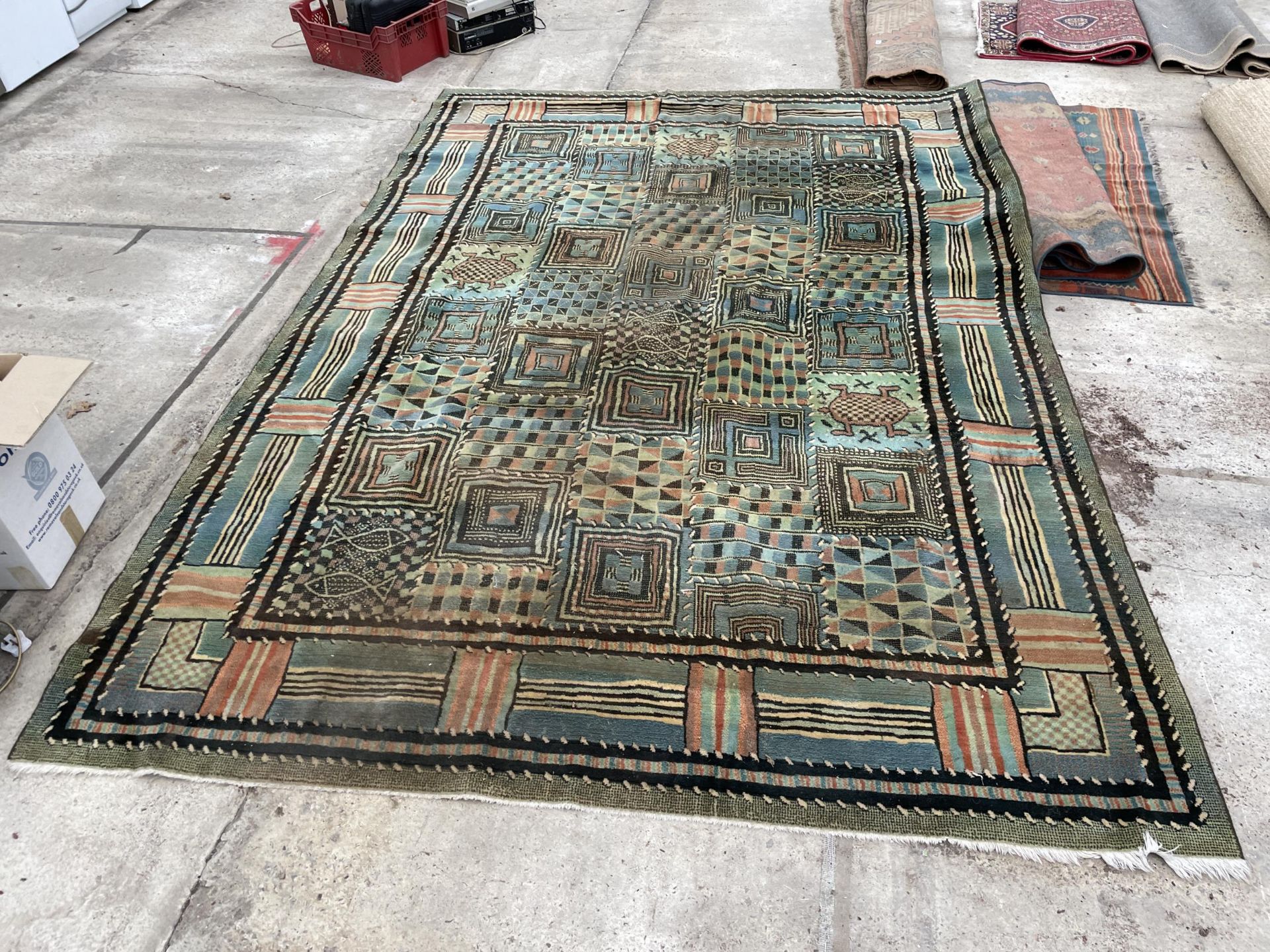 A LARGE GREEN PATTERNED FRINGED RUG