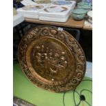 A VERY LARGE BRASS CHARGER WITH AN EMBOSSED SCENE OF A MIDDLE AGES FEAST DIAMETER 72CM