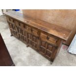 A MODERN SPANISH STYLE BEECH SIDEBOARD WITH RAISED PANELS AND IRONWORK HINGES AND HANDLE, 79" WIDE