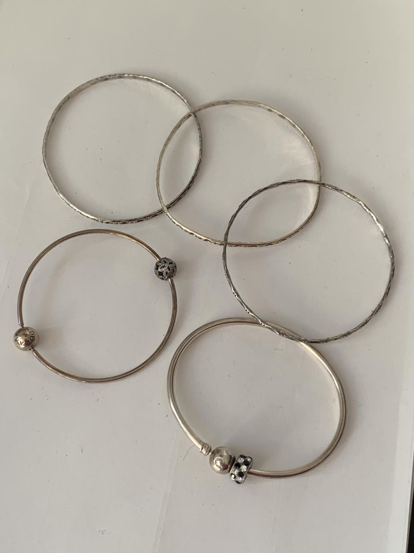 FIVE VARIOUS SILVER BANGLES TO INCLUDE A PANDORA AND A CHAMILIA