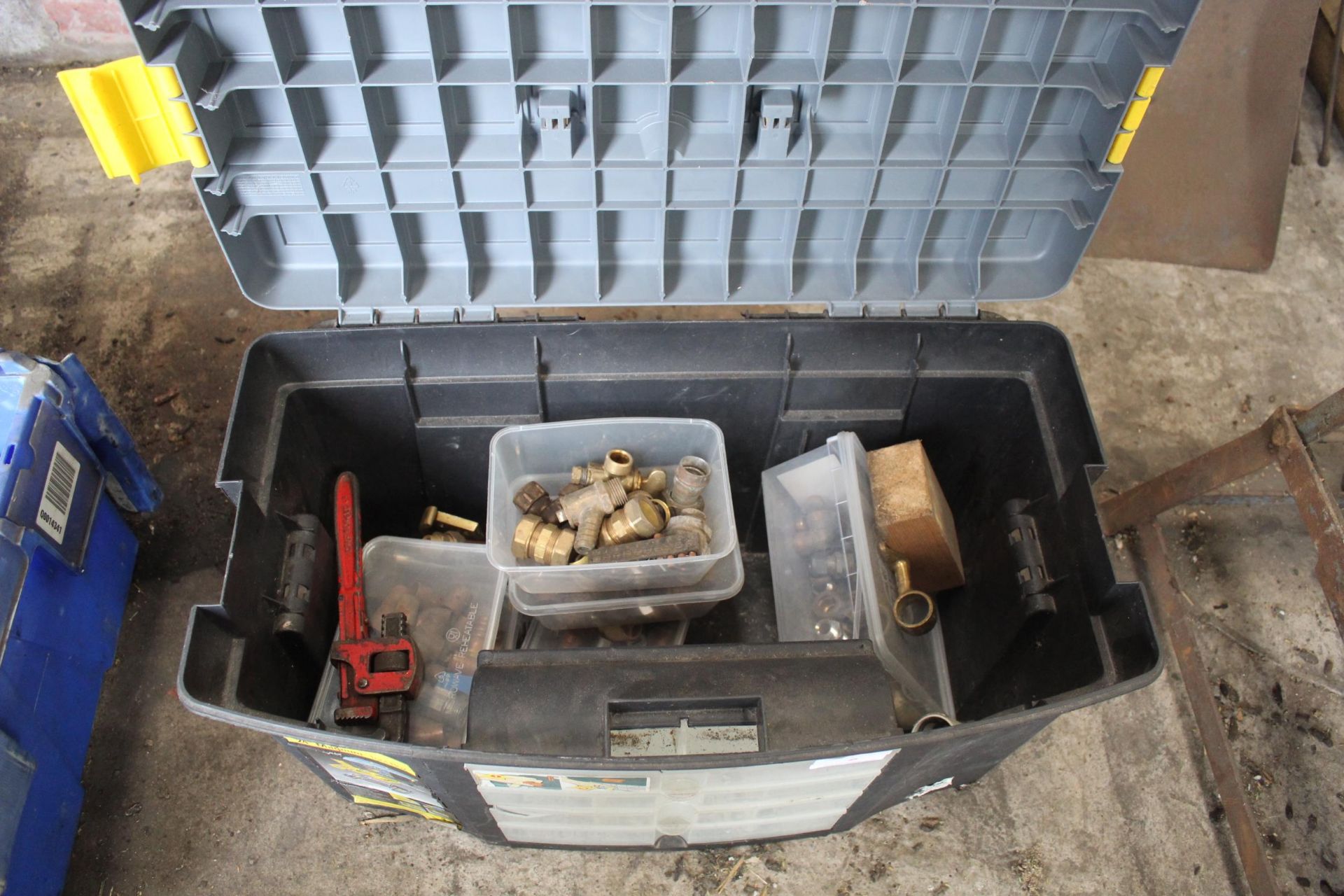 A PLASTIC TOOL BOX WITH AN ASSORTMENT OF BRASS PIPE FITTINGS AND A PAIR OF STILSENS