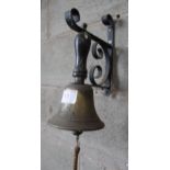 A VINTAGE BRASS BELL ON A WALL HANGING BRACKET