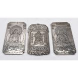 Three Chinese silver coloured ingots, two depicting Buddha and the other the god of wealth