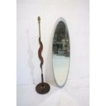 A mid century oval bevel-edge wall mirror along with a standard lamp.