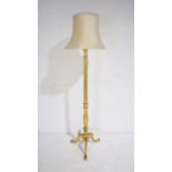 A gilt standard lamp on tripod base with shade.