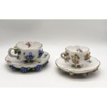 Two Meissen floral encrusted cups and saucers with blue crossed swords mark, slight nibbles to rim