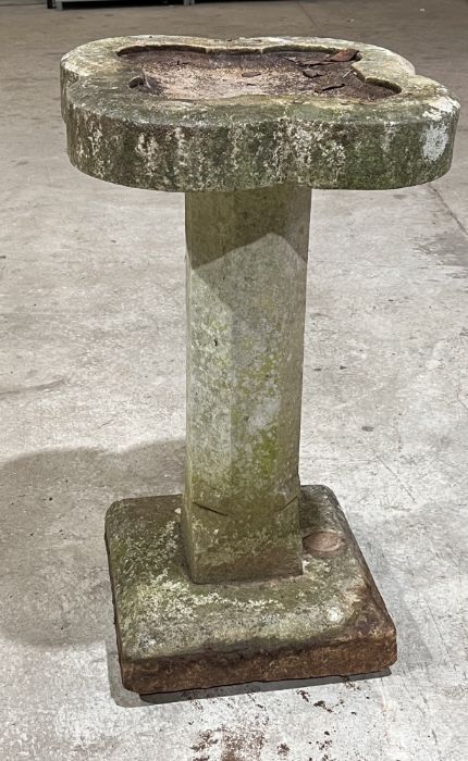 A one piece reconstituted stone quatrefoil bird bath.