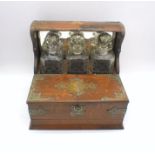 A turn of the century oak tantalus with three decanters and compartment under.