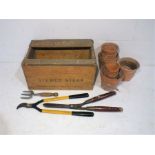A small quantity of terracotta garden pots along with a vintage wooden crate and gardening tools.