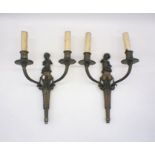 A pair of bronze classical wall mounted light fittings with putti's atop a column with swag