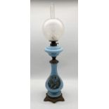 An blue opaline oil lamp with frosted shade and printed scene of two seated children to base -