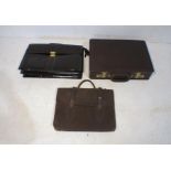 A leather briefcase along with two leather satchels.