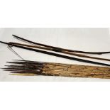 A collection of wooden tribal bows and arrows consisting of three bows and a number of wooden arrows