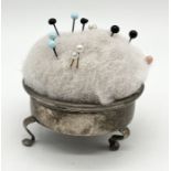 A hallmarked silver pincushion on three feet