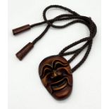 A pendant in the form of a Japanese mask (character marks to reverse) on braided hair necklace