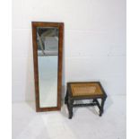 A small bobbin-turned stool along with a rectangular wall mirror.