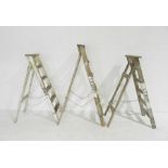 Three vintage wooden stepladders.