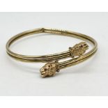 A 9ct gold torque bangle with leopard head finials with inset ruby eyes (A/F), weight 8.6g