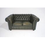 A green leather two seated Chesterfield sofa with button-back detailing, length 147cm.