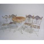 A weathered metal bistro set consisting of a table and four chairs