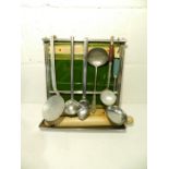 A vintage tile backed aluminium wall hanging kitchen utensil stand with utensils