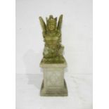 A weathered lava stone figure of a Balinese deity on a concrete plinth - height 103cm
