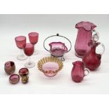 A collection of cranberry glass including decanter, jug, bon bon dish and four pieces of miniature