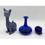A blue glass piggy bank and decanter (no stopper) along with a pottery cat