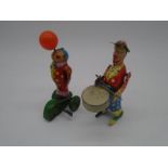 Two clockwork tinplate models of circus clowns, one drumming, the other balancing a ball on it