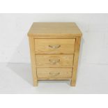 A modern oak bedside chest of three drawers