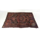 An Eastern red ground rug with geometric designs - 201cm x 130cm