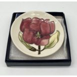 A boxed Moorcroft pin dish in the magnolia pattern numbered 75/94 - diameter 10cm