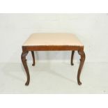 An upholstered dressing table stool on cabriole legs