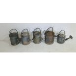 A collection of five vintage galvanised watering cans