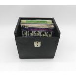 A collection of 7" vinyl records by The Beatles and related artists contained within a vintage carry