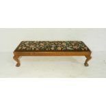 A long footstool with tapestried upholstery, raised on claw and ball feet - length 99cm