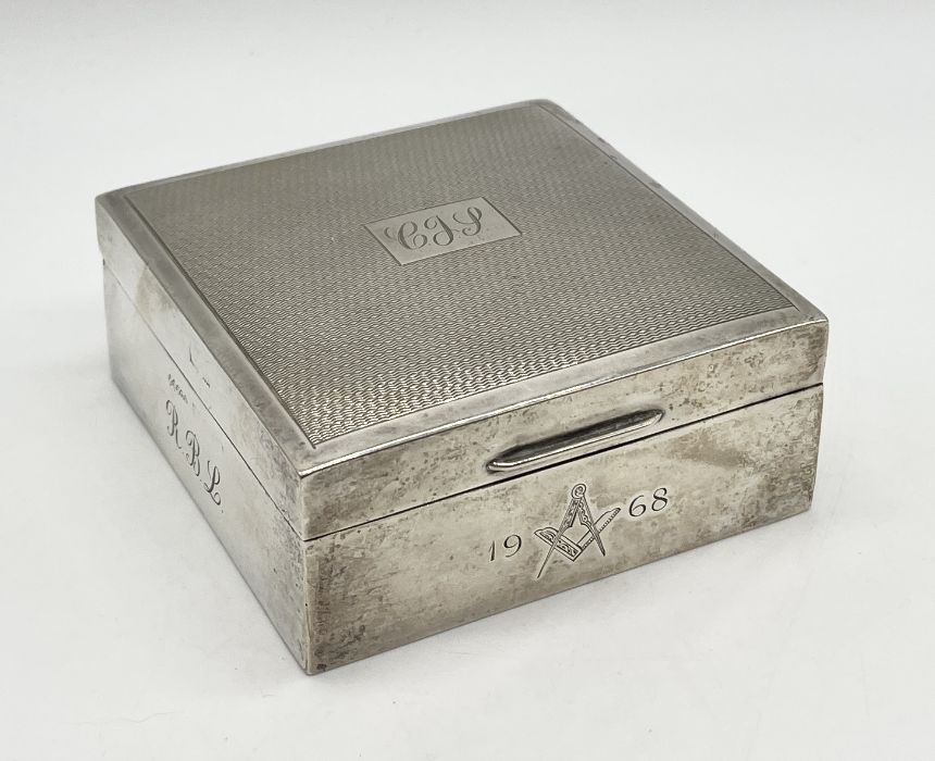 A silver cigarette box with engine turned decoration and Masonic symbol to front, dated 1968