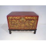 A lacquered Oriental trunk on stand with gilded decoration depicting exotic birds, fish etc -